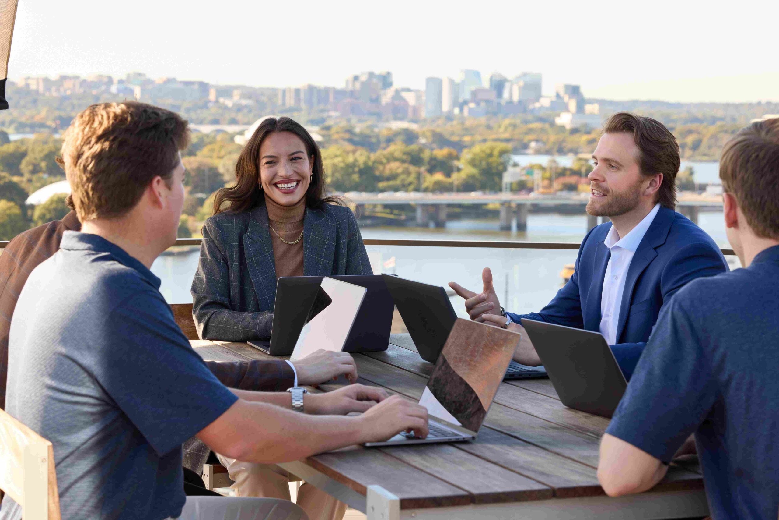 Real estate students meet at a table outdoors with cityscape in the background.