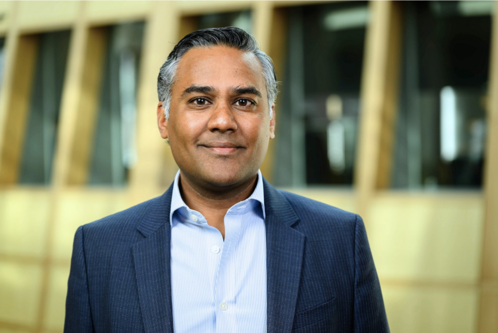 Board Member, Ankur Shah in a light blue button down and a navy suit jacket.