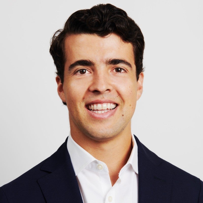 Board Member, Alejandro Ernst, wearing a white button down shirt and a black dress suit.
